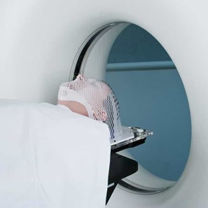 Man with mesh over his face goes into an MRI machine for a brain scan after a traumatic brain injury